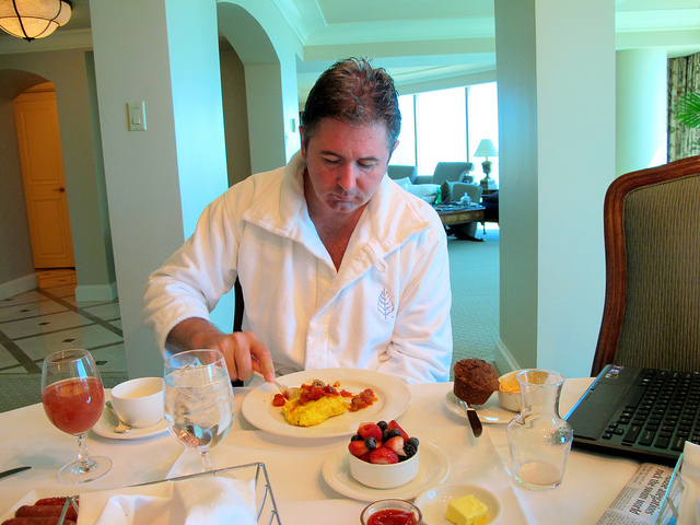 A man eating an omelette in a hotel suite.