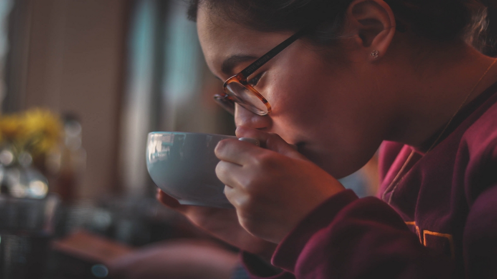A woman peacefully drinking a warm cup of ginseng tea.