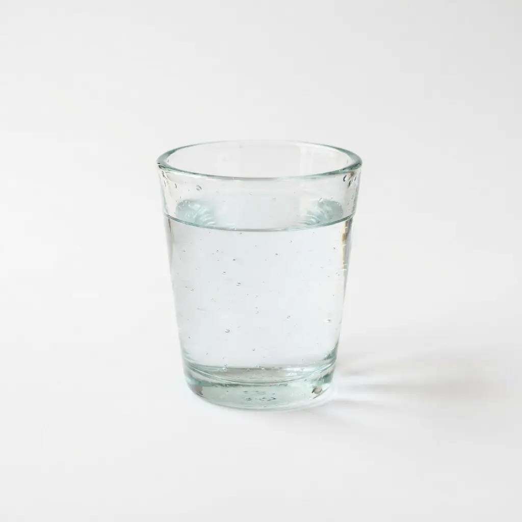 Water in a clear drinking glass on a clean white background.